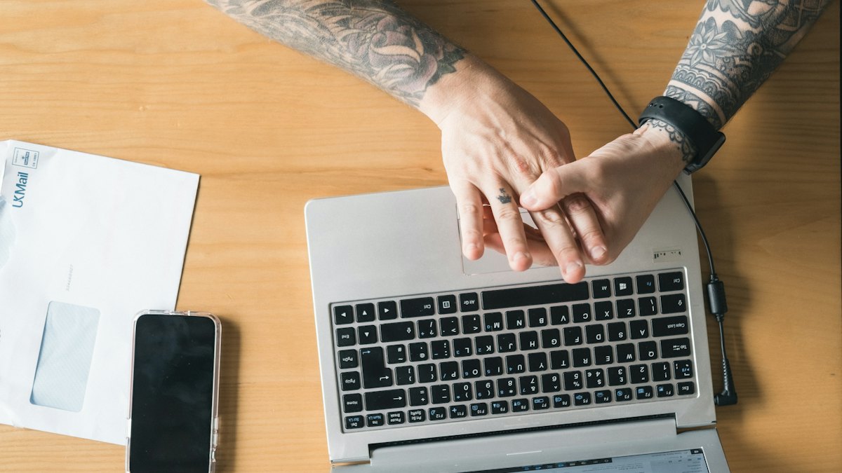 Osoba pracująca na laptopie przy drewnianym stole